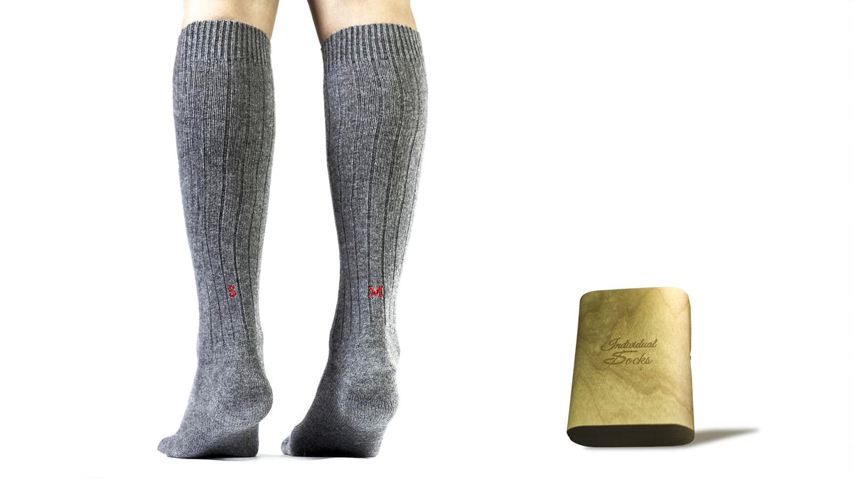 calze in cashmere blend blu navy da uomo con l'iniziale ricamata artigianalmente, accanto al Cofanetto in Legno