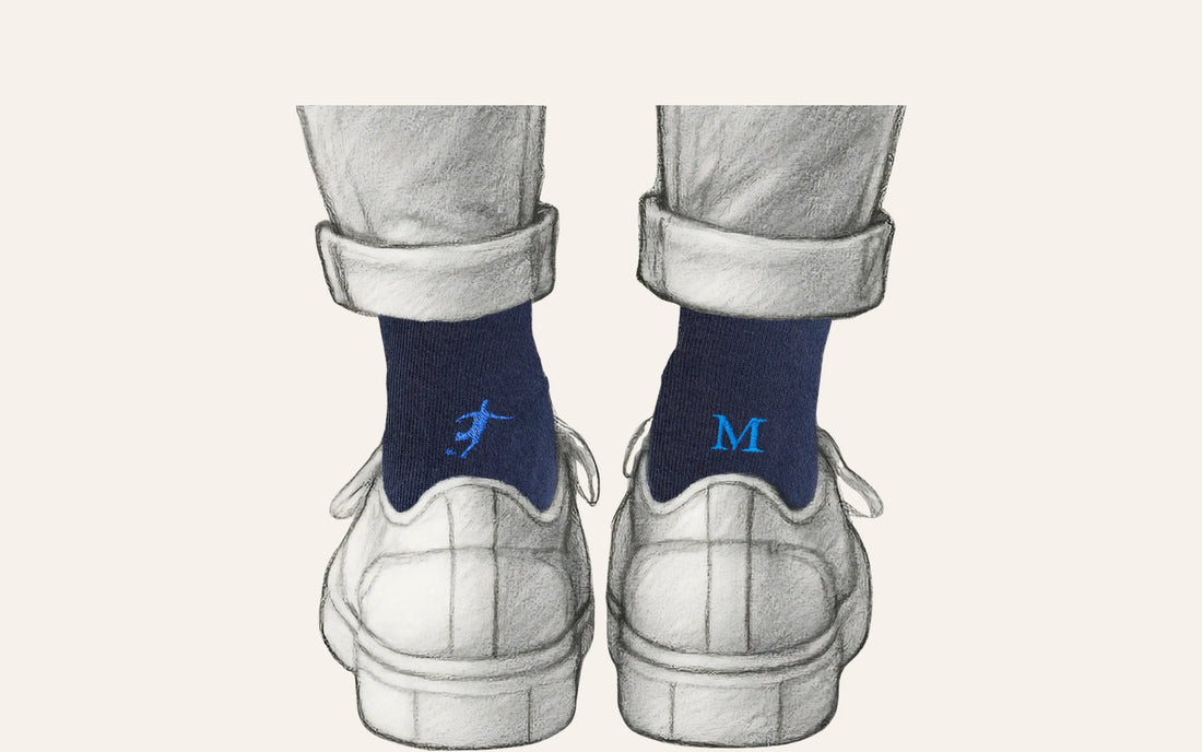 regalo per chi gioca a calcio: calze blu Individual Socks con il calciatore ricamato in blu royal su una calza e l'iniziale sull'altra, indossate sotto un pantalone