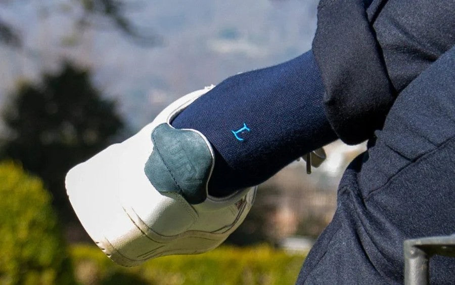 regalo per chi gioca a golf: calze blu con il simbolo del golf e l'iniziale ricamata, accanto a una pallina e a un tee