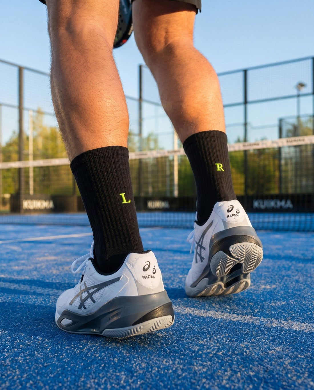 Regalo per chi gioca a padel: calze nere con il simbolo del padel e l'iniziale ricamata in giallo fluo, accanto a una racchetta